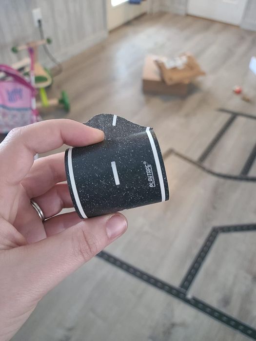 close-up of a reviewer holding the tape, showcasing its white road-like lines