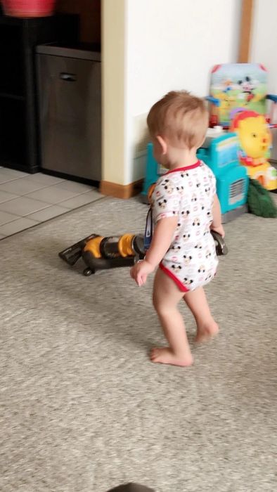 A reviewer's photo of their child using the toy vacuum