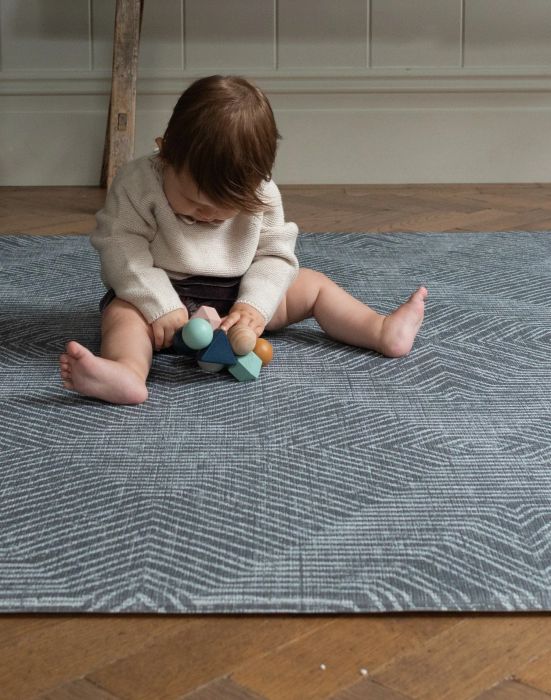 A baby sitting on a blue-patterned play mat