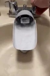 A gif showing water flowing through a faucet extender attached to a faucet