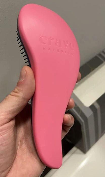 A reviewer shares a photo of the ergonomically designed pink brush
