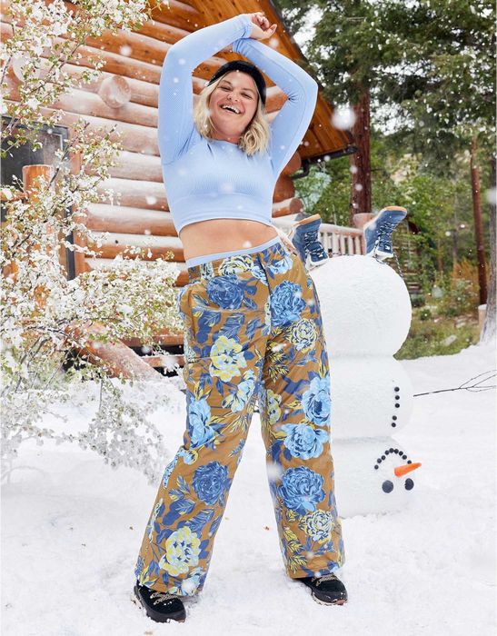 The model is dressed in brown snow pants featuring a light and dark blue floral pattern.