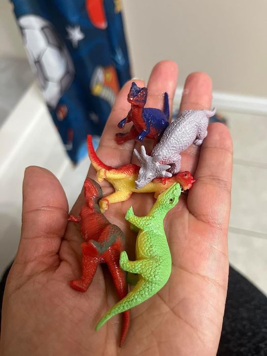 A reviewer’s hand holding the dinosaur toys