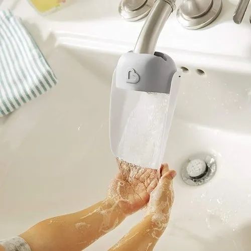 A child using a sink extender to wash their hands at the faucet