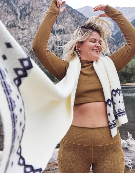 Model wearing a white, fuzzy scarf with black patterns at each end.