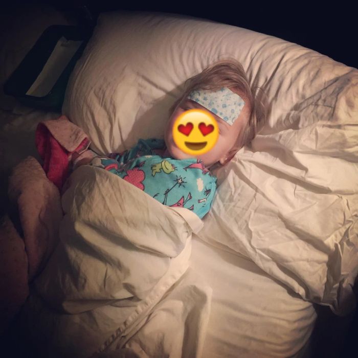 A reviewer's photo of their child in bed with a gel sheet on their forehead