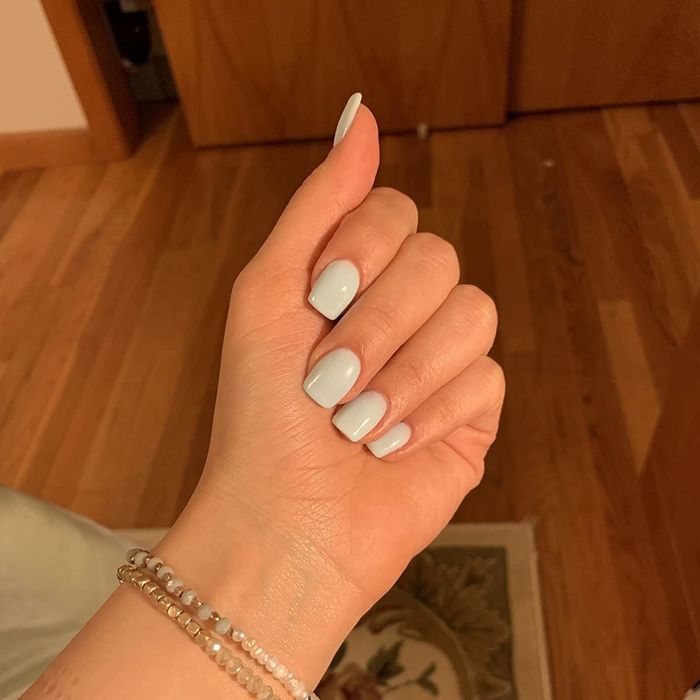 A reviewer displaying baby blue square-shaped nails