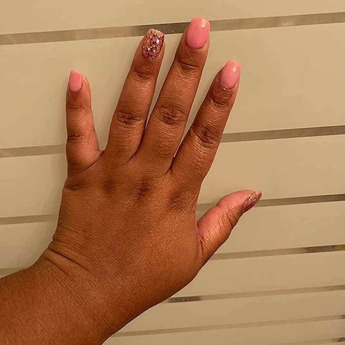 A reviewer showcasing pink nails with glitter accents on their ring finger and thumb