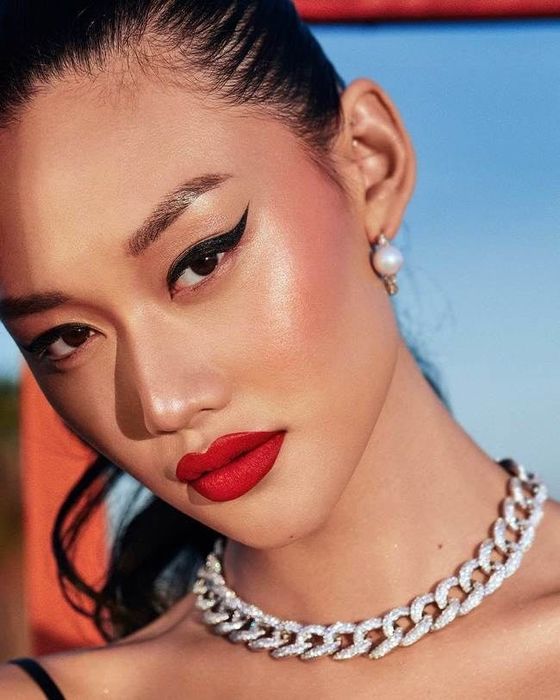 A model showcasing the vibrant red lip paint paired with a bold black cat-eye liner