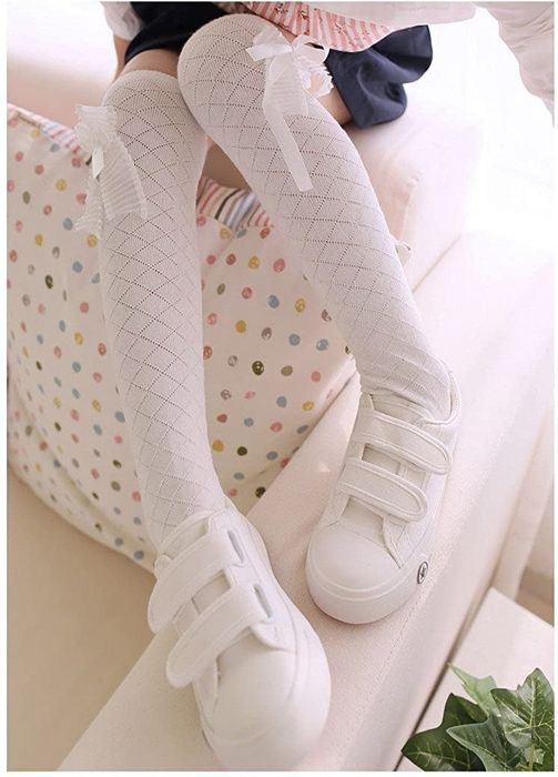 A young girl dressed in knee-high white stockings with an adorable bow, featuring an argyle pattern.