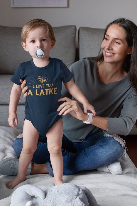 A child in a blue onesie that reads 