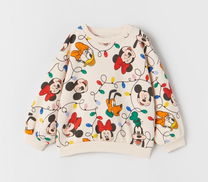 An off-white sweater adorned with Mickey, Minnie, Donald, Goofy, Daisy, Pluto, and Christmas lights.