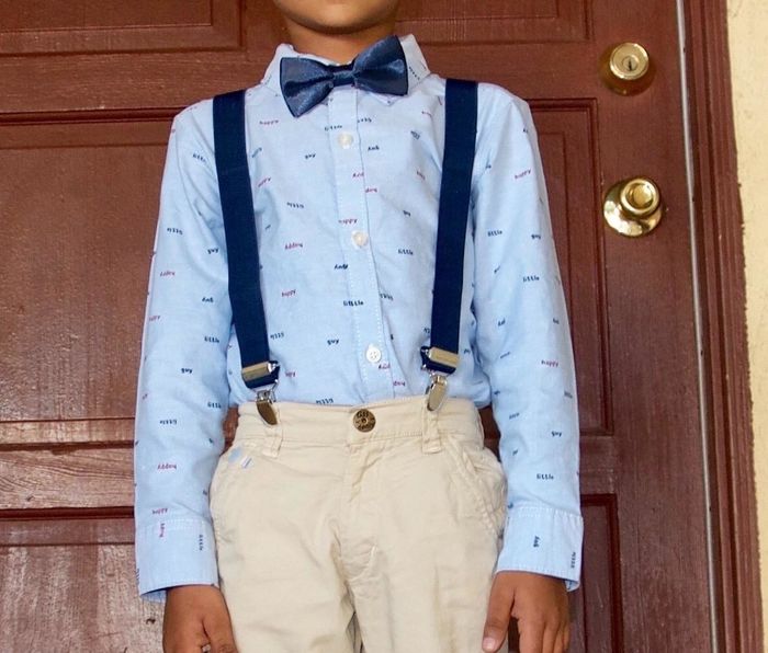 A child dressed in a blue bowtie and suspenders.