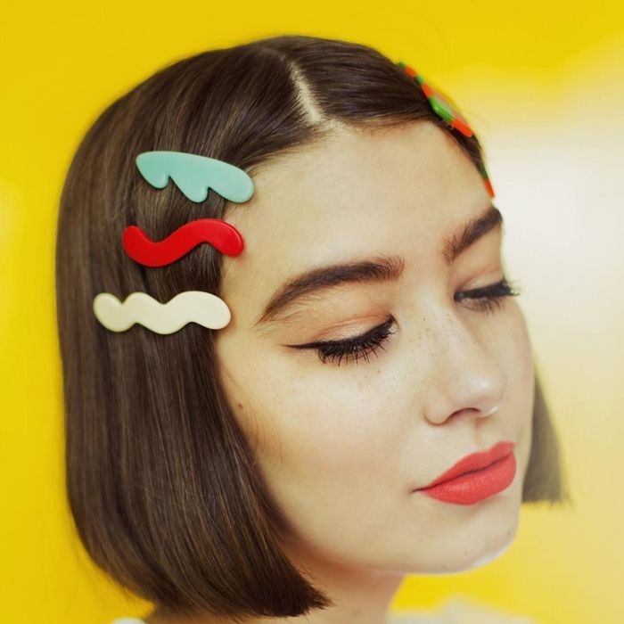 three clips in different colors clipping back model's bangs