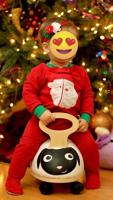 A reviewer's child wearing a red sleeper onesie with Santa on it.