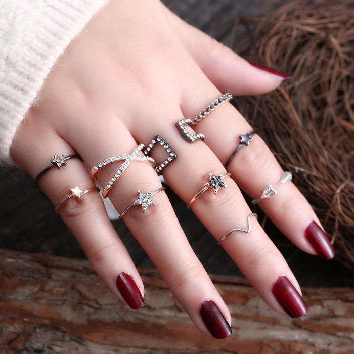 the rings displayed on a hand, featuring a mix of knuckle rings and midi rings