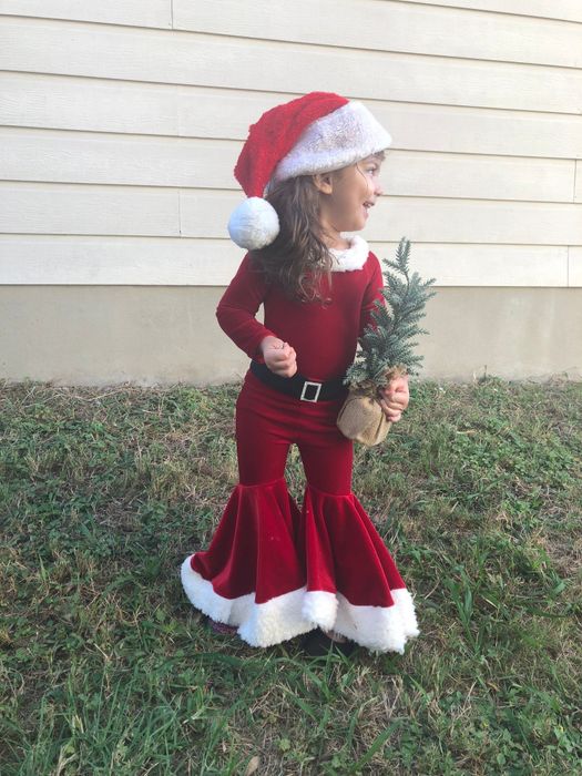 a child dressed in a velvet Santa outfit complete with flare pants