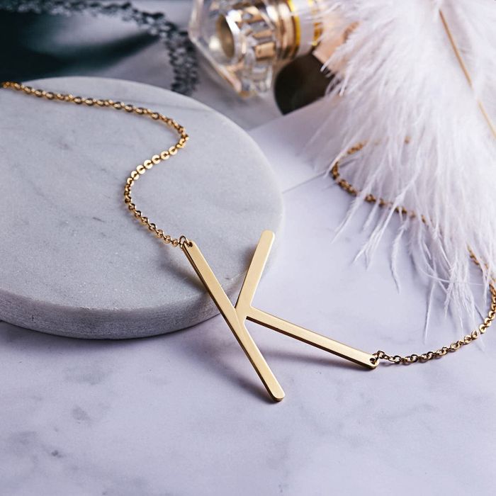 the gold necklace featuring the letter
