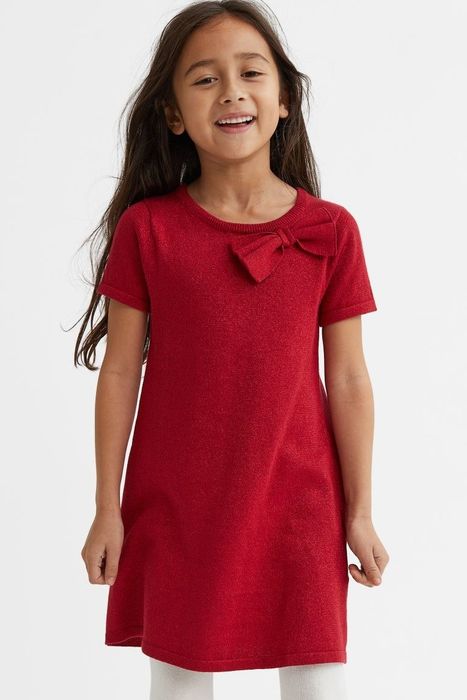 A child wearing a red, glittery dress with a bow.