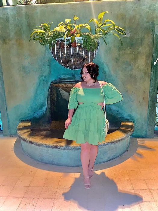 A reviewer wearing the green square neck mini dress paired with heels, sharing their thoughts on its style and fit.