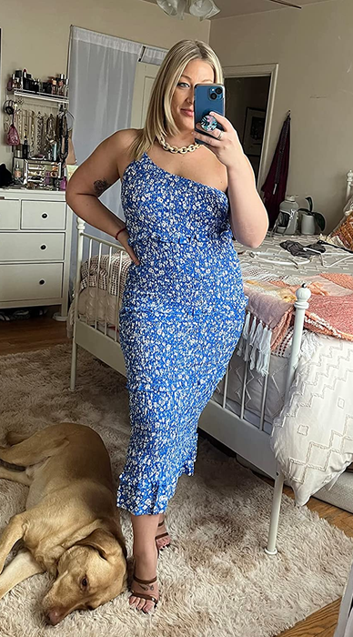 A reviewer showcasing the one-shoulder blue floral dress