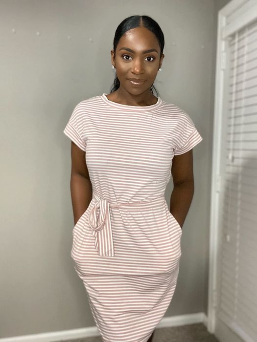 A reviewer wearing the pink striped dress with an adjustable tie waist