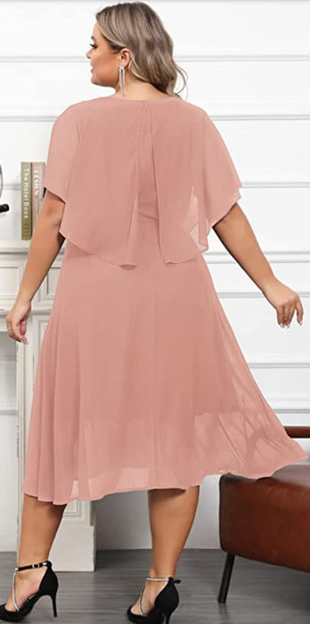 The same model showcasing the dress in pink, highlighting the cape from the back