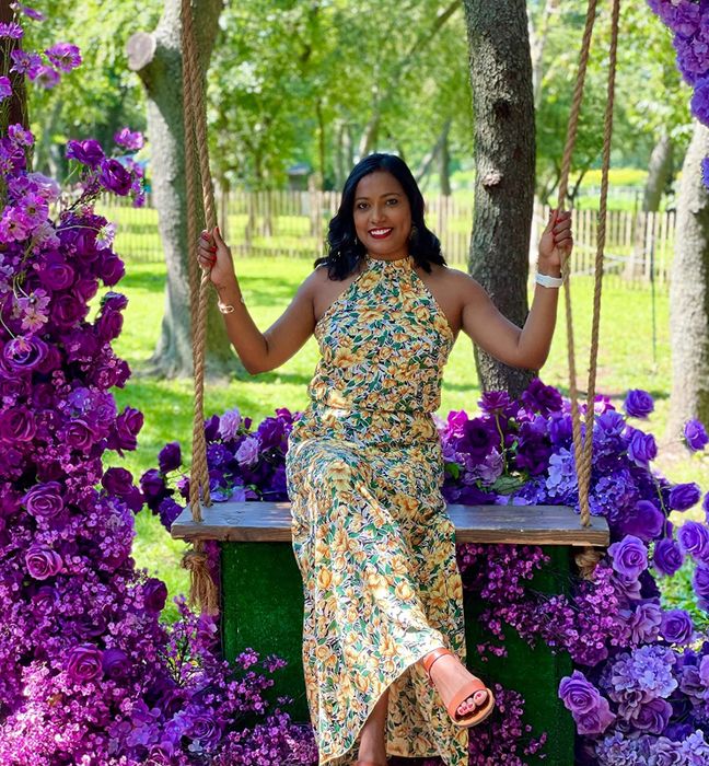 A reviewer wearing the dress in a vibrant yellow floral print