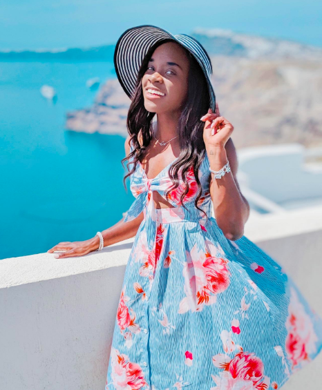 A reviewer wearing the blue dress adorned with vibrant pink flowers
