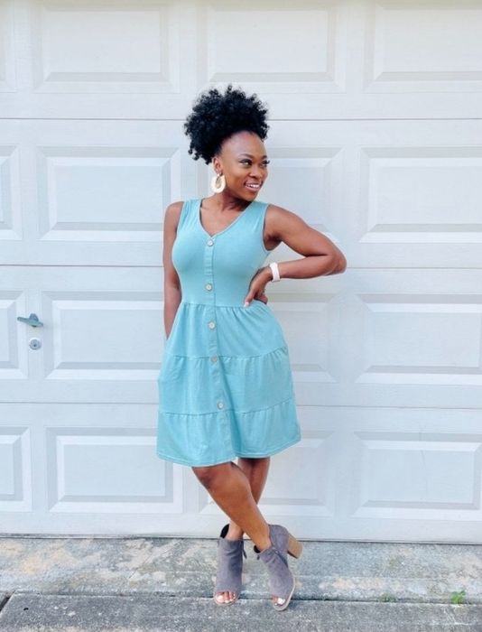 A reviewer showcasing a light blue V-neck sleeveless button-down dress
