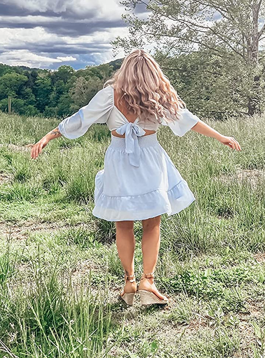 A reviewer showcasing the back of the light blue dress with its tie-back detail