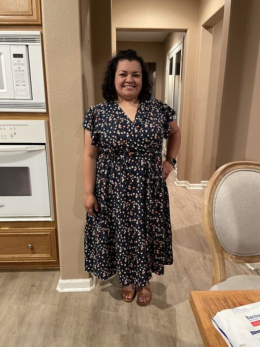 A reviewer wearing a black floral dress with pink and white accents
