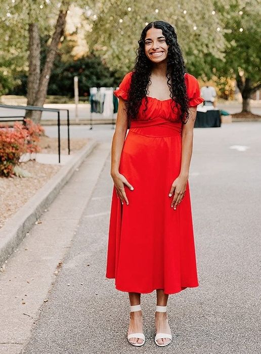 A reviewer wearing the dress in a striking red color