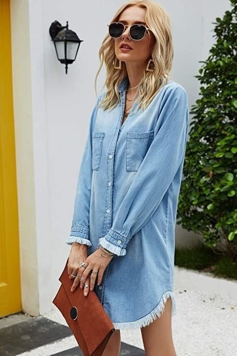 A model styled in a fully buttoned denim dress, accessorized with numerous pieces to elevate the look