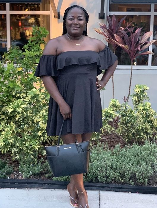A reviewer modeling the same strapless off-shoulder ruffled mini dress in black