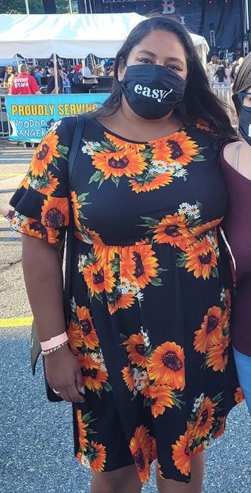 A model wearing a short ruffle-sleeve swing dress in a black sunflower print