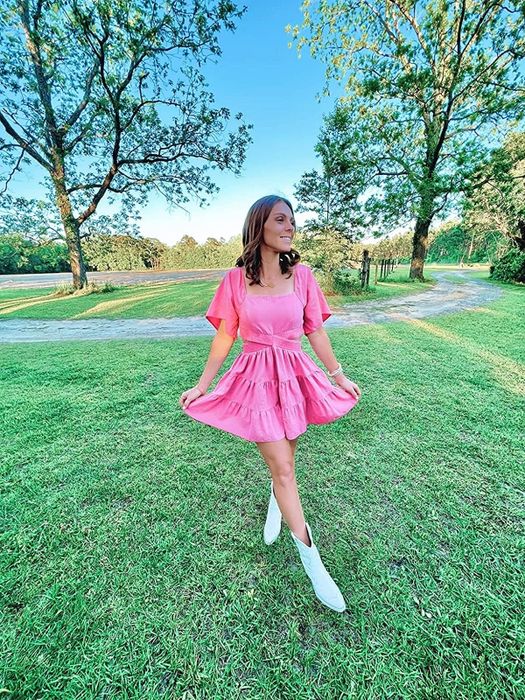 A reviewer in the pink tiered dress, praising its design, comfort, and suitability for special occasions.