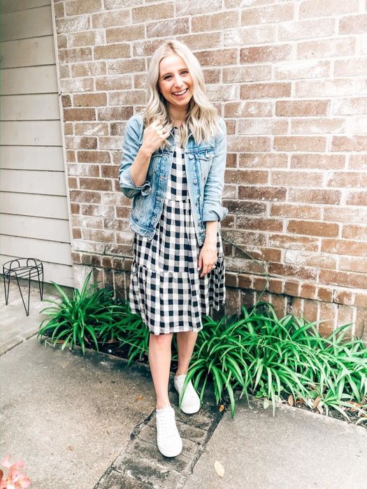 A reviewer wearing the black and white dress paired with white sneakers and a denim jacket