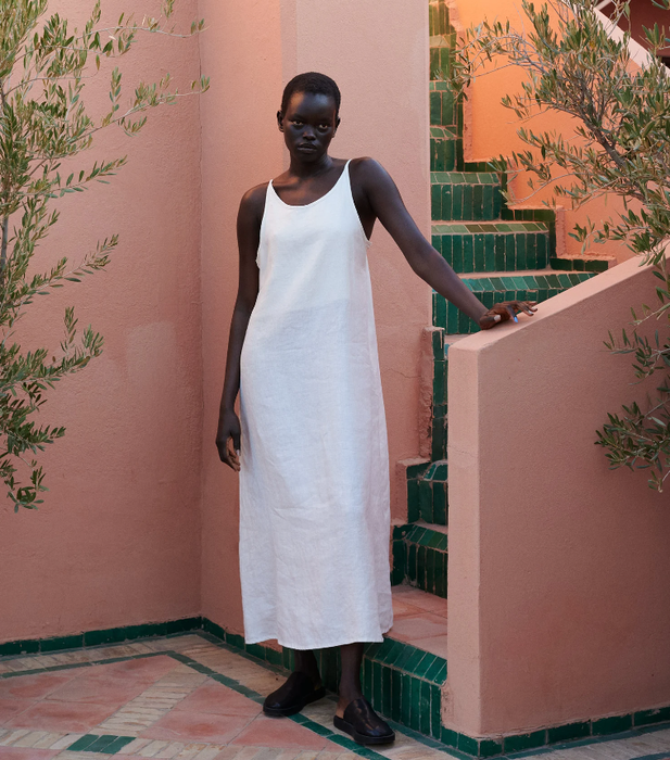 Model wearing a white linen dress that gracefully flows down to the ankles