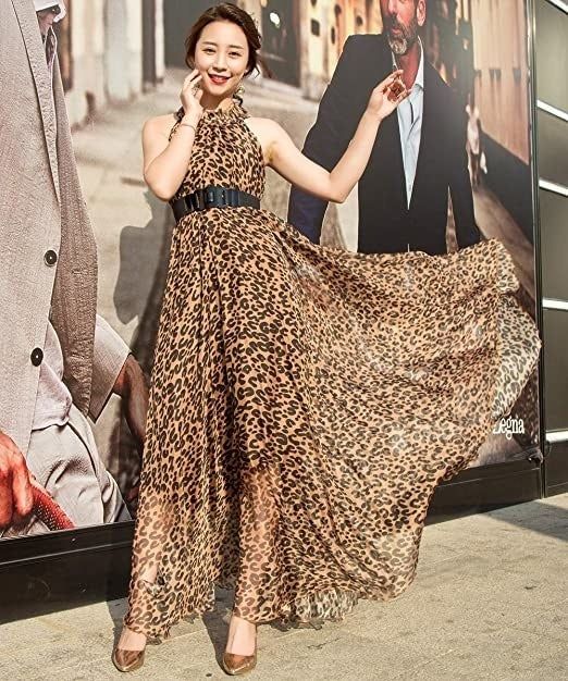 A model wearing a long halter dress in leopard print, accentuated with a waist belt