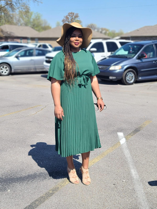 A reviewer wearing the dress in a vibrant green shade