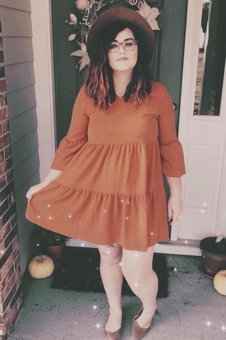 reviewer wearing an orange dress paired with a hat and flat shoes