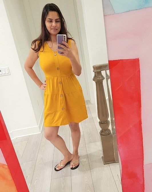 A reviewer modeling the same yellow V-neck sleeveless button-down dress