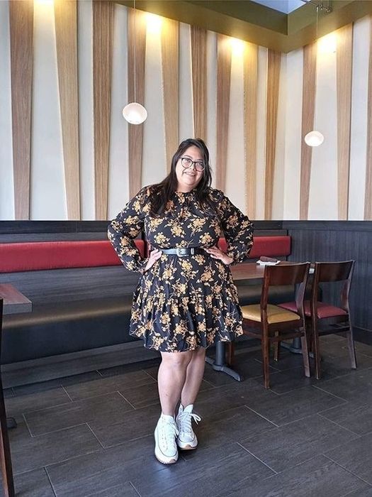 A reviewer wearing the black dress with gold accents