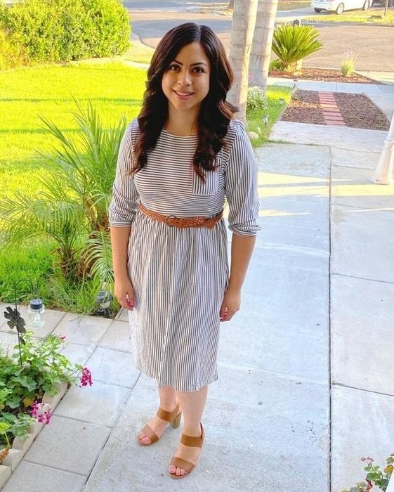 A reviewer in a black and white striped dress styled with brown shoes and a belt