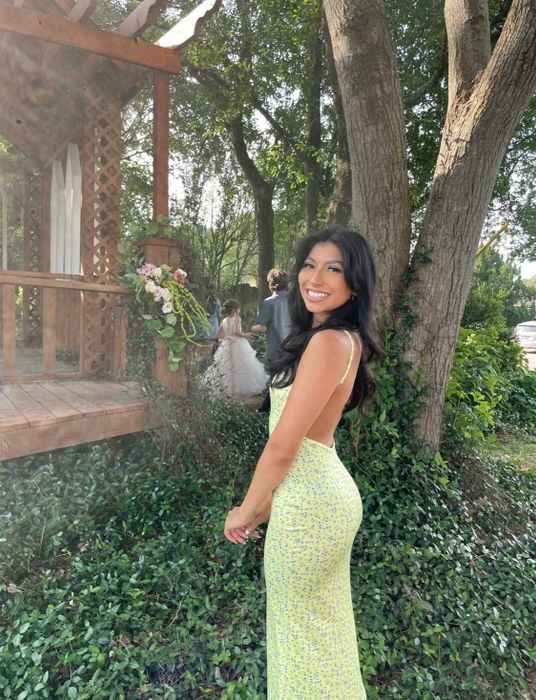 A reviewer in the yellow floral maxi dress, sharing their experience with its vibrant color, fit, and suitability for warm-weather events.
