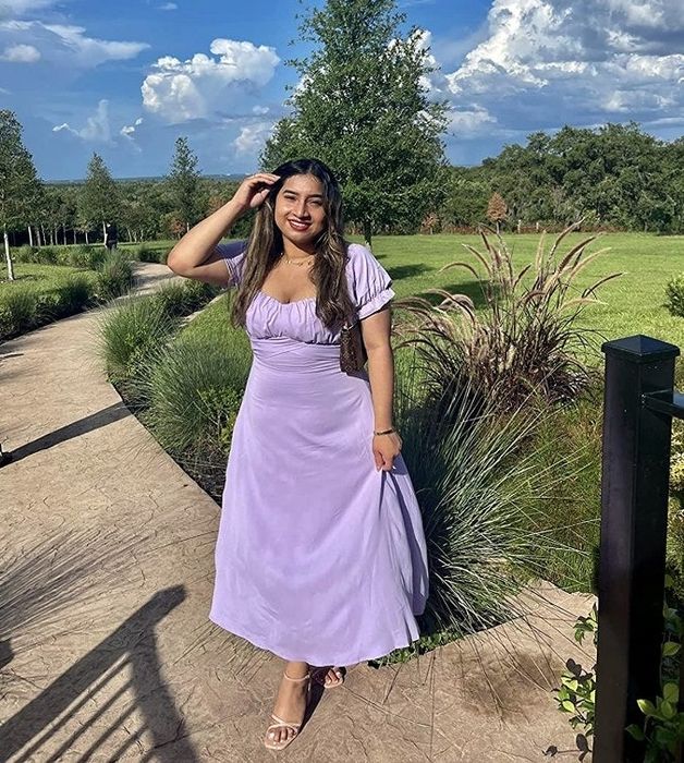 A reviewer wearing the dress in a regal purple tone