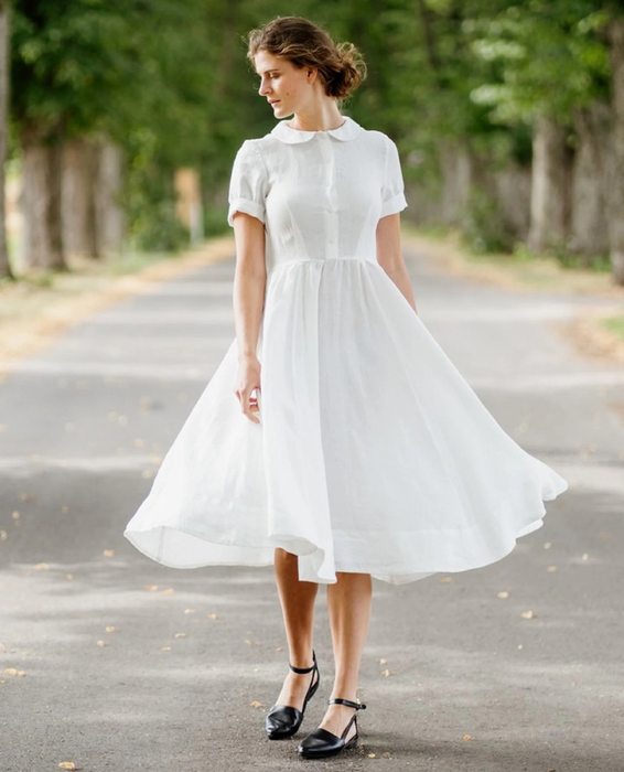 The model is wearing a white dress fully buttoned up.