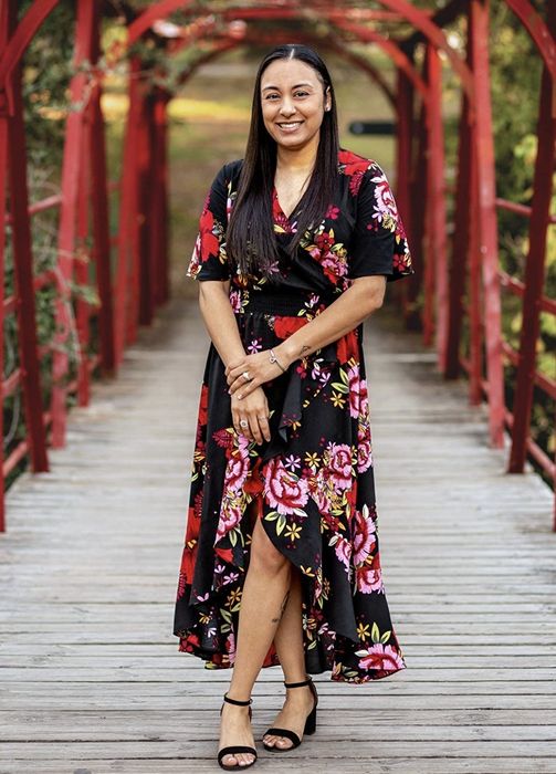 The reviewer modeling the black dress with pink and red floral patterns