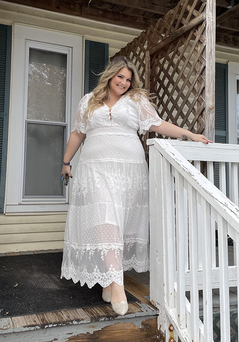 A reviewer showing off the elegant white lace dress in a chic pose